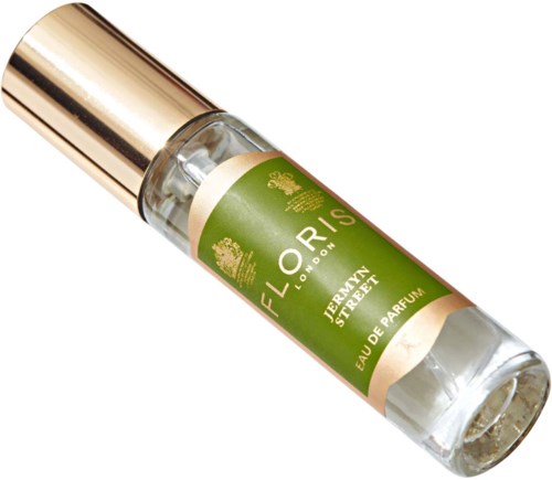 Een kleine parfumfles met een gouden dop, groen-witte etiket, en helder glas dat parfum binnen toont.