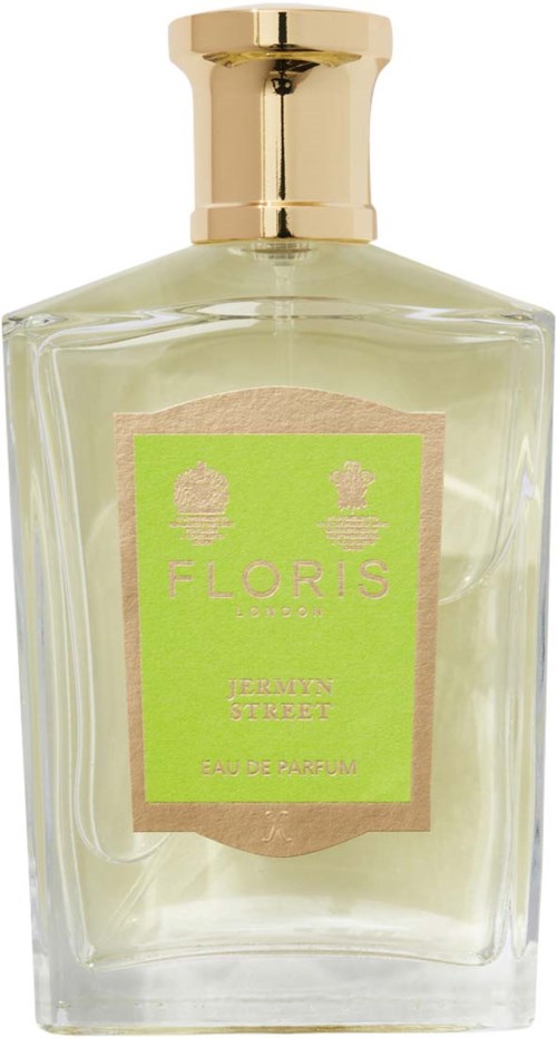 Ein Parfümflasche mit goldener Kappe, klarem Glas und grünem Etikett. Das Etikett hat Text und kleine Pflanzensymbole.