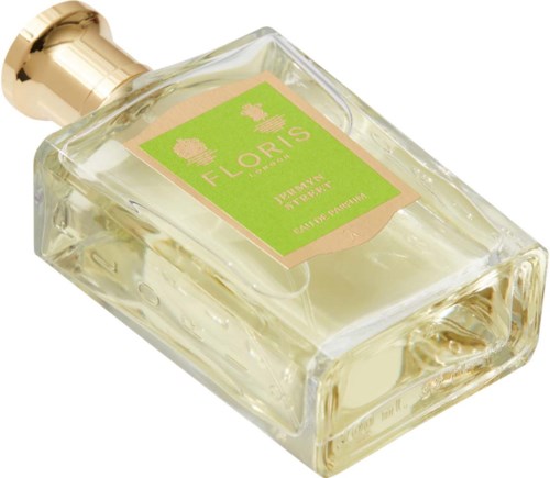 Eine klare Parfümflasche mit goldfarbenem Deckel, etiketti 'FLORIS.' Sie enthält hellgelbe Flüssigkeit und liegt schräg.