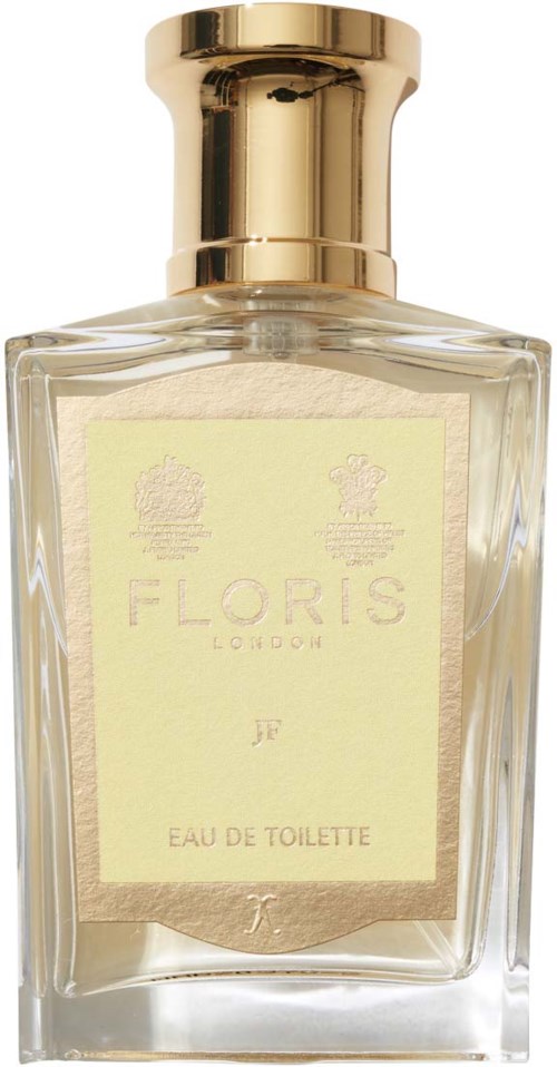 Een parfumfles met een gouden dop, doorzichtig glas en een lichtgele label met 'Floris London JR Eau de Toilette.'