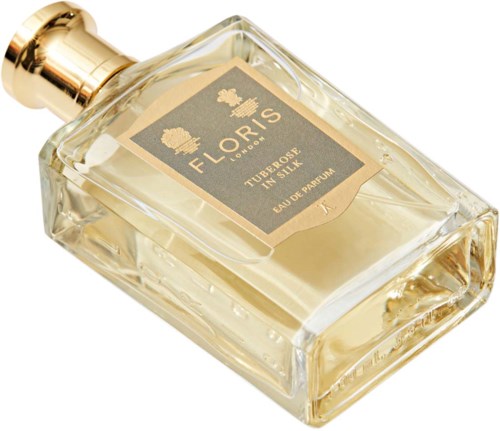A perfume bottle with a gold cap and a light-colored liquid inside. The label says 'FLORIS, LONDON, TUBEROSE, EAU DE PARFUM.'