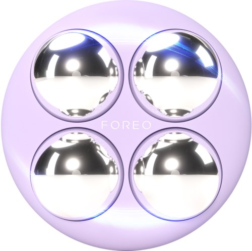 Een ronde apparaat met vier spiegelachtige metalen ballen en een paarse achtergrond. Het woord "FOREO" staat in het midden.