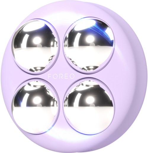 Een ronde apparaat met vier glanzende metalen ballen binnenin, gemerkt 'FOREO', in een lichte paarse rand.