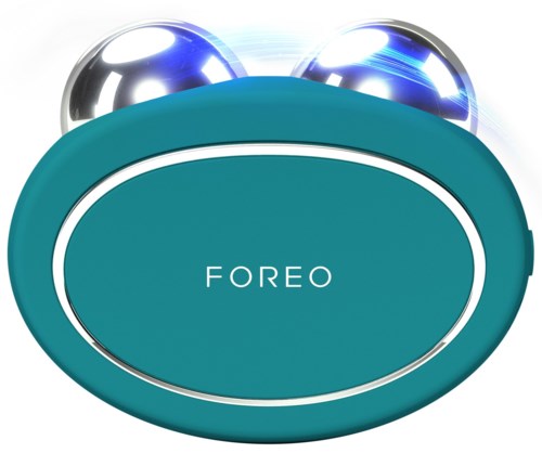 Een teal gekleurde apparaat met de naam 'FOREO', met twee glanzende metalen bollen bovenaan.