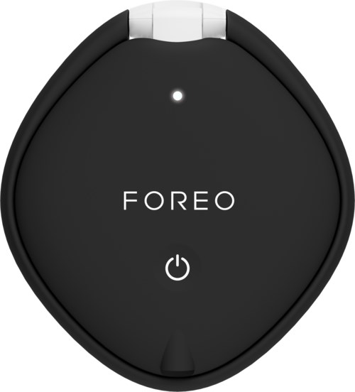 En enhet märkt 'FOREO' med en strömknapp och ett litet ljus på en svart yta.