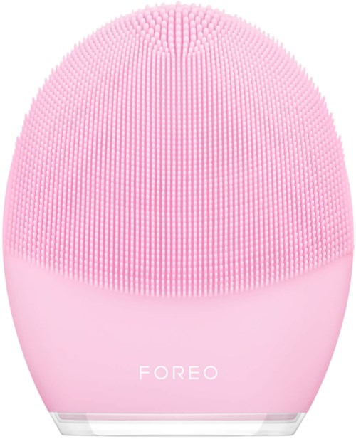 En rosa, äggformad silikonapparat med små borstehår, märkt 'FOREO' längst ner.