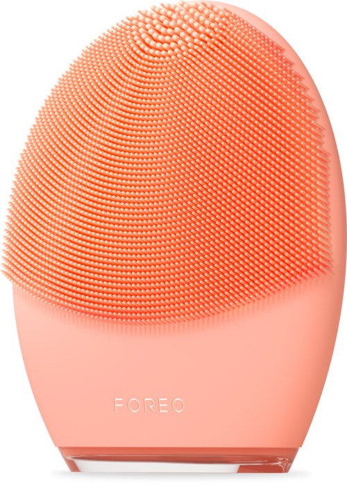 Een perzikkleurige gezichtsschoonheidsborstel met veel zachte borstels en het woord 'FOREO'.