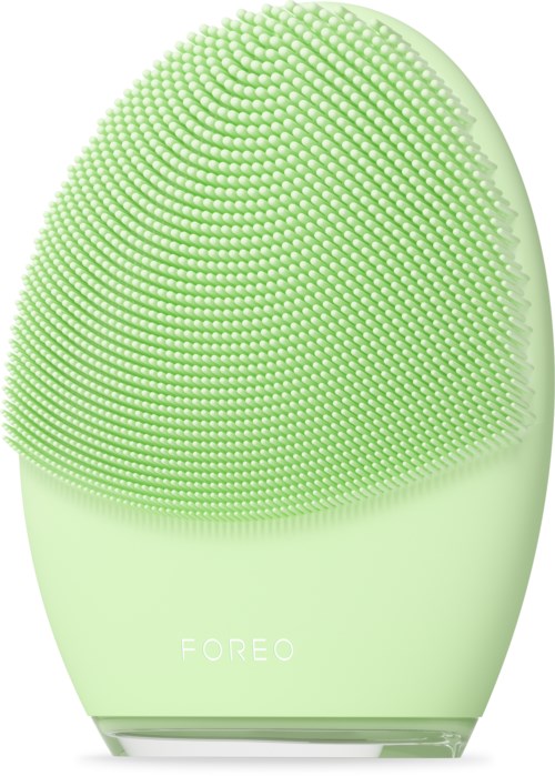 Een groen, ovaalvormig gezichtsapparaat met veel kleine borstelhaartjes, met het label 'FOREO'. Het lijkt op een schoonmaak- of huidverzorgingshulpmiddel.