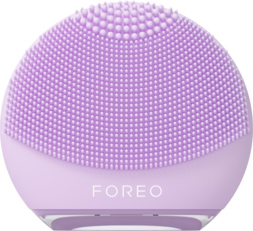 Een ronde, paarse apparaat met veel kleine zachte borstels, gemarkeerd "FOREO." Het lijkt op een huidverzorgingsapparaat.