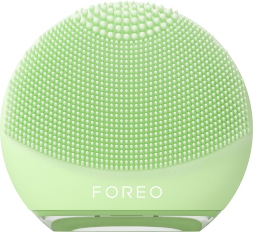 Een ronde, groene gezichtsreinigingsapparaat met kleine borstelharen en het woord 'FOREO'.