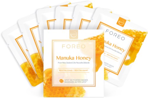 Vijf gezichtsmasker verpakkingen met manuka honing ontwerp en merk, in helder oranje en wit, met honingafbeeldingen.