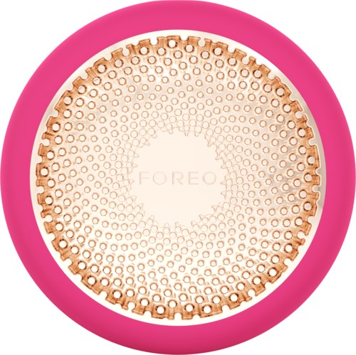Een ronde roze apparaat met een beige getextureerd oppervlak en het woord "FOREO" in het midden.
