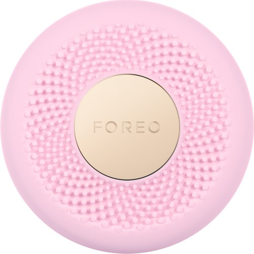 En rund, rosa ansiktsrengöringsenhet med texturerade knappar och en beige mittdel märkt 'FOREO'.