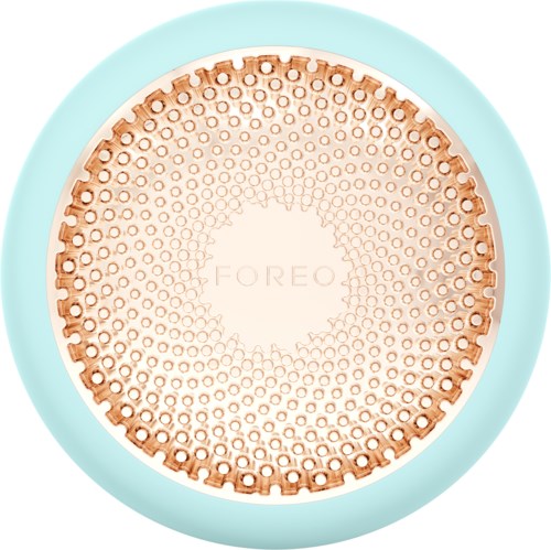 Een ronde apparaat met een blauwe rand en een koperen midden met vele kleine gaatjes, gemarkeerd 'FOREO'.