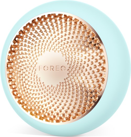 Een ronde, lichtblauwe apparaat met een gouden, getextureerde oppervlakte en de merknaam "FOREO" in het midden.