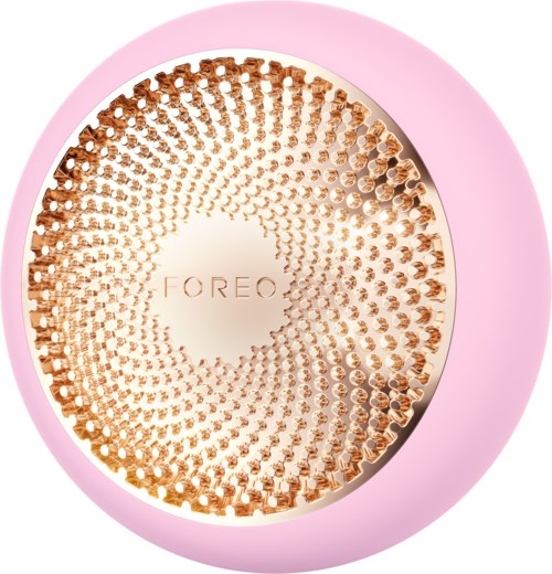 Een ronde, roze apparaat met een gouden, getextureerde ronde bovenkant met de merknaam Foreo.