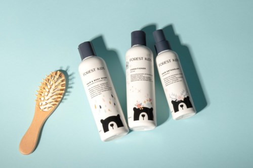 Three bottles of Forest Kids shampoo and a wooden hairbrush on a blue background.