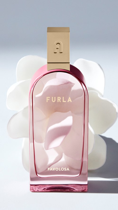 En rosa parfyllflaska märkt 'Furla Favolosa' med ett guldlock, belysning bakom med vita moln eller skum.