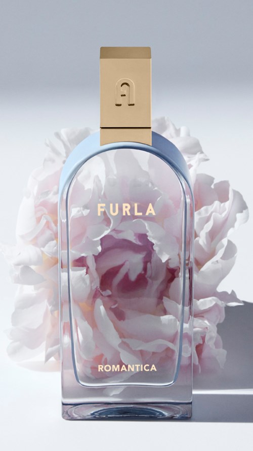 En parfymflaska märkt 'Furla Romantica' med ett ljusblått lock, omgiven av rosa och vita blommor.