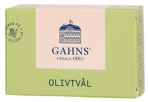 En grön och ljusrosa tvålkopp med GAHS-loggan och ordet OLIVTVÅL under.