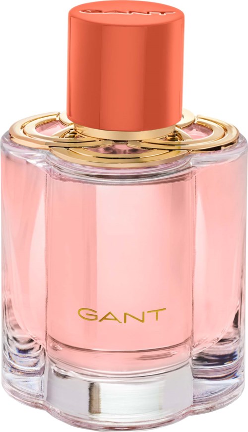 Eine rosa Parfümflasche mit korallfarbenem Deckel und goldenen Akzenten, mit GANT beschriftet, elegantes Design.
