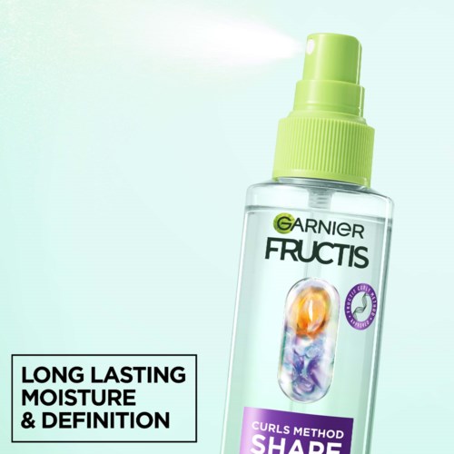 Een duidelijke sprayfles met groen pompje, gemarkeerd Garnier Fructis Curls Method, bevordert langdurige hydratatie en definitie van krullen.