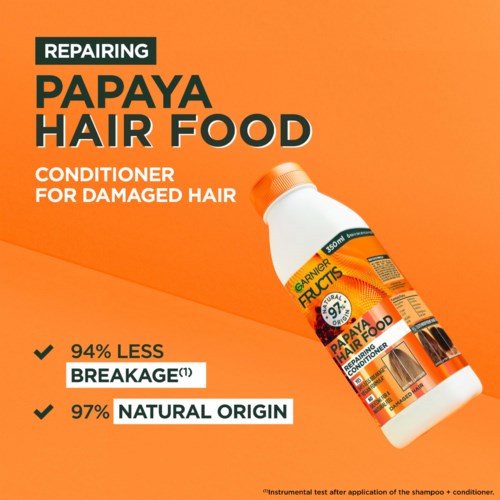 Haarconditioner voor beschadigd haar genaamd Papaya Hair Food, met oranje en witte fles, benadrukt 94% minder breuk en natuurlijk.