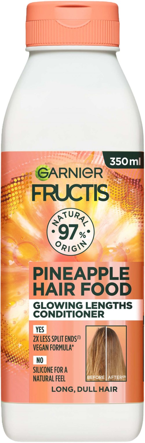Een witte fles met een perzikkleurige deksel, gelabeld als Garnier Fructis Pineapple Hair Food voor glanzend, lang, dof haar.