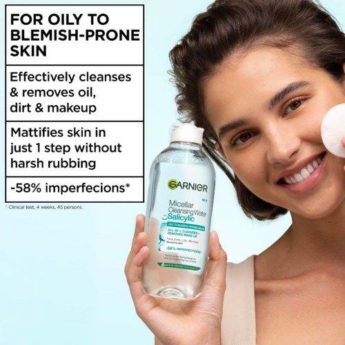 A woman holds Garnier micellar water, smiling, with facial cleansing benefits for oily skin and fewer imperfections.