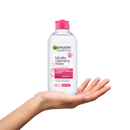 Een hand houdt een fles Garnier micellair water, bedoeld om make-up te verwijderen en geschikt voor de gevoelige huid.