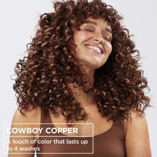 Kvinna med lockigt hår som ler, och marknadsför Cowboy Copper hårfärg som håller i upp till 4 tvättar.