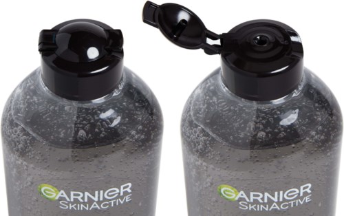 Two bottles with black caps, one open showing a scoop. They are Garnier skincare products with clear liquid inside.