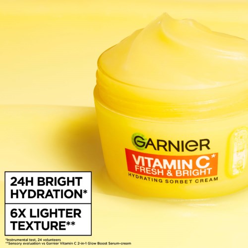 En gul burk med lock som innehåller Garnier Vitamin C ansiktskräm, som lyfter fram ljusare hud och återfuktning.