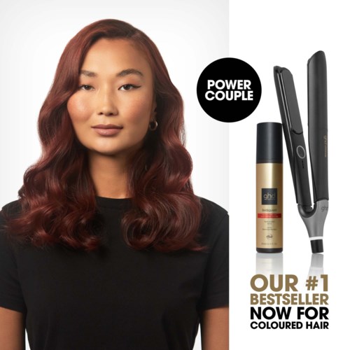 A woman with styled red hair, black shirt, and subtle makeup, alongside hair styling tools and a hair spray.