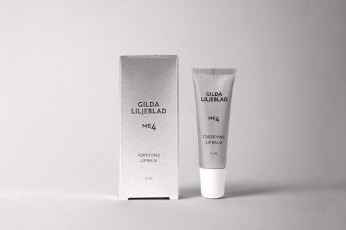 Een lipbalsemtube naast een doos op een effen achtergrond, beide gelabeld Gilda Liljeblad No. 4, Fortifying Lip Balm.