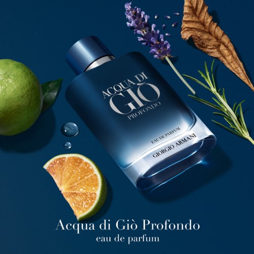 Eine blaue Parfümflasche mit der Aufschrift 'Acqua di Giò Profondo' umgeben von Zitrone, Lavendel, grünen Blättern und einem getrockneten Blatt.