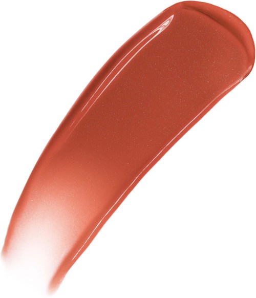 Een streek van perzikkleurige lippenstift met glinsterende deeltjes op een witte achtergrond.