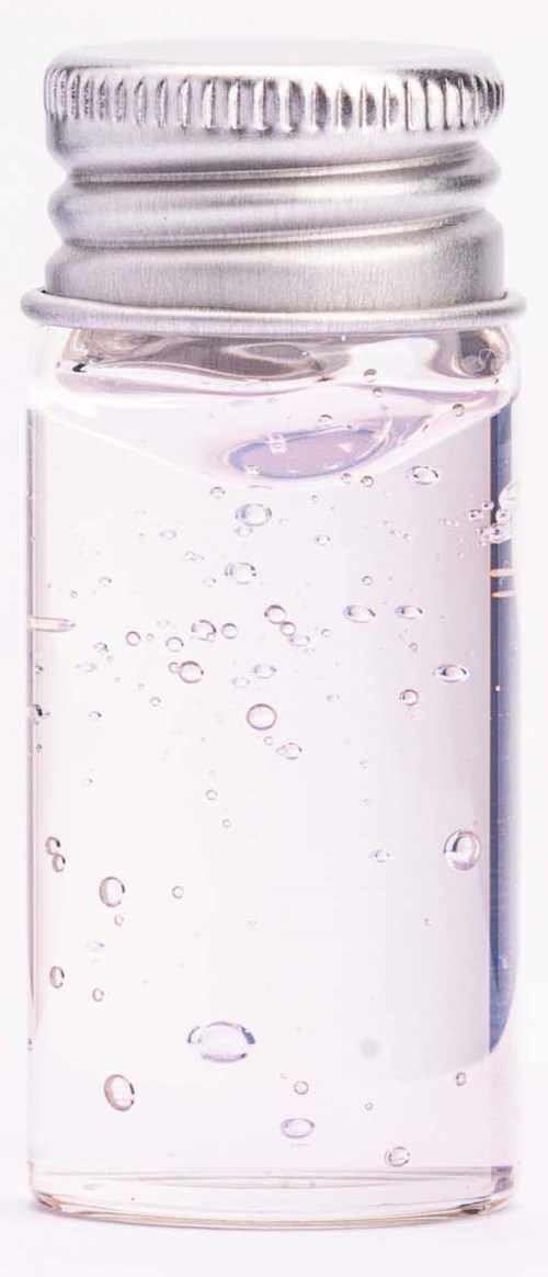 Kleines Glasflasche mit Metallschraubverschluss, gefüllt mit klarer Flüssigkeit und Bläschen.