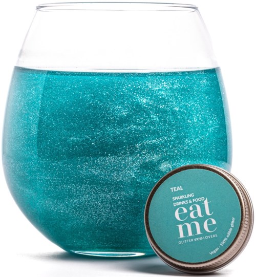 Ein klares Glas mit hellblauer funkelnder Flüssigkeit und eine rundes teal-Behälter mit der Aufschrift 'eat me' am unteren rechten Rand.