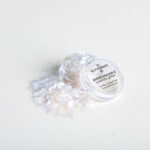 Een kleine container met biologisch afbreekbare cosmetische glitter met wat morsen eromheen.