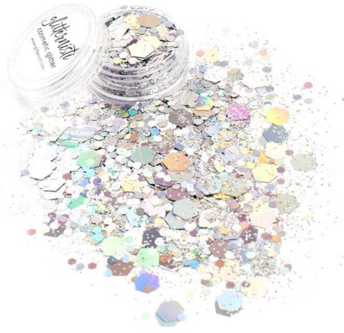 Een kleine container met iriserende, hexagonale glitters die in pastelkleuren verspreiden.