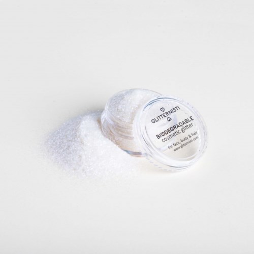 Een kleine container glitter, die op een witte ondergrond morst.
