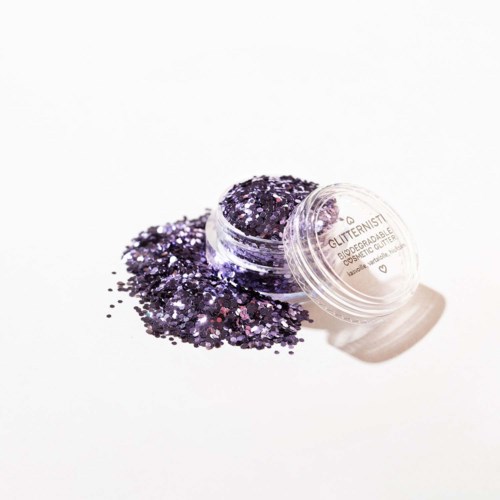 Een kleine open verpakking met paarse glitter die op een witte ondergrond uitloopt.