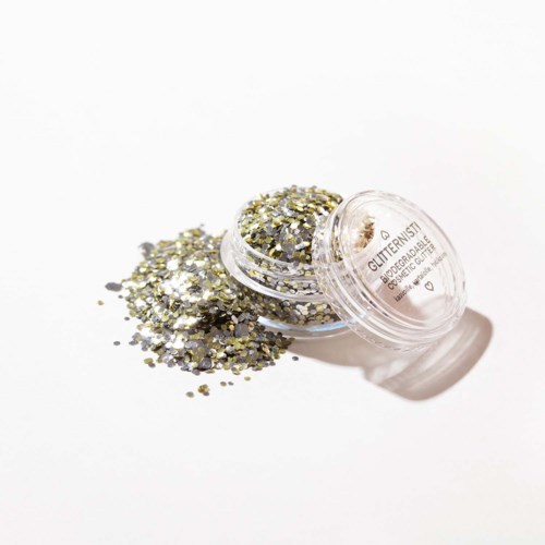 Kleine container met zilveren en gouden glitter uitgespat op witte ondergrond.