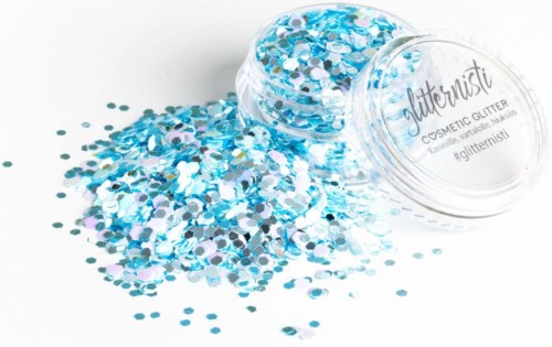 Een doorzichtige container is omgevallen en verspreidt blauwe en zilveren glitters op een witte ondergrond. De deksel heeft de tekst 'Glitterfisti' en hashtags.