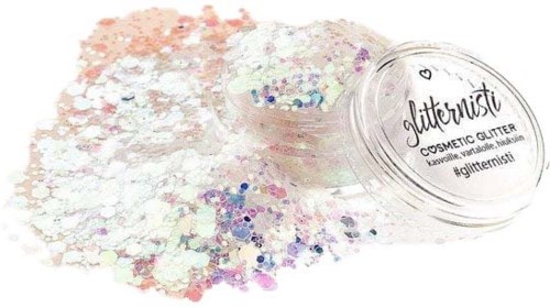Een potje glitter morst kleurrijke deeltjes op een witte ondergrond. Het potje labelt 'Jittermist Cosmetic Glitter' met hashtags.
