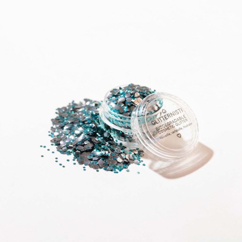 Een kleine container met blauw en zwart glitter die op een wit oppervlak is gemorst.