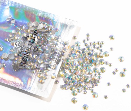 Kleine glanzende rhinestones die uit een doorzichtige plastic zak met 'GIRLFRIEND' label vallen.