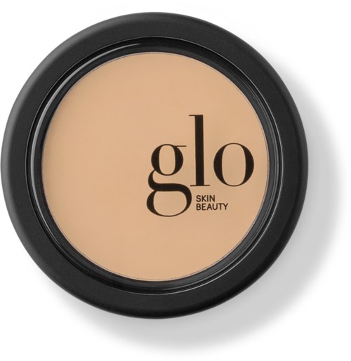 A compact makeup container with beige cream inside, black outer case, and the words "glo SKIN BEAUTY" on top.