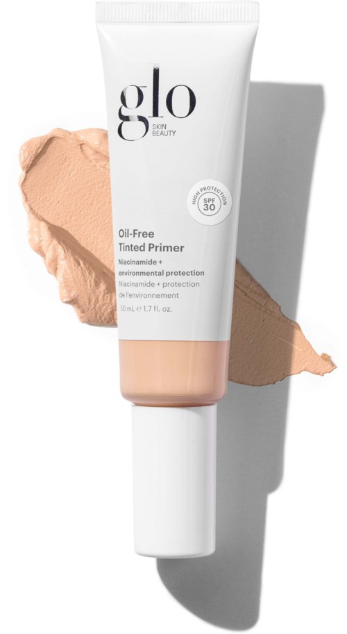 A white tube of Glo tinted primer with SPF 30, standing upright with beige product spread beside it, casting a shadow.